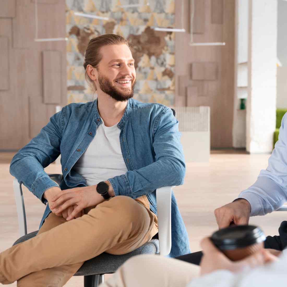 a man sitting in a chair talking to another man